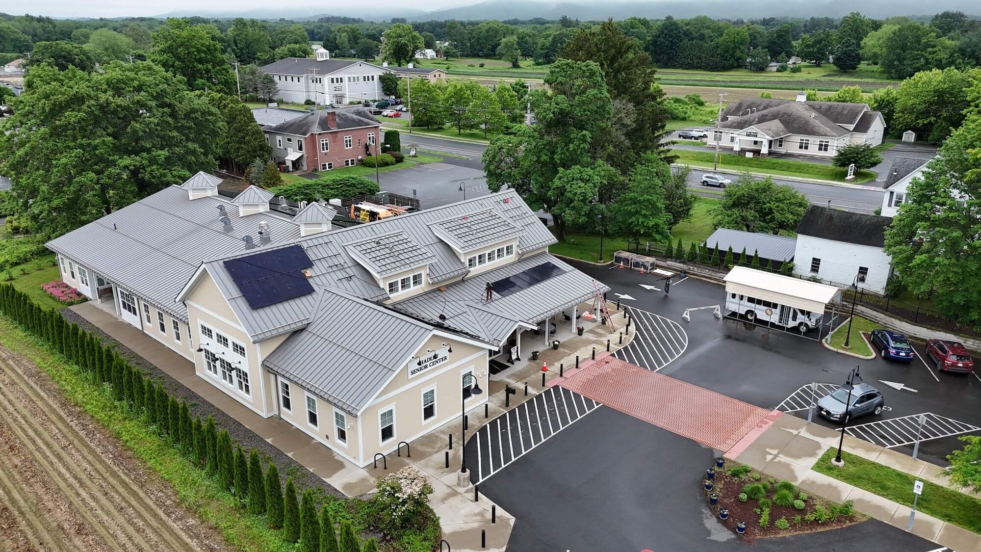 Solar panels installation on the roof of a senior center in a green suburban area.