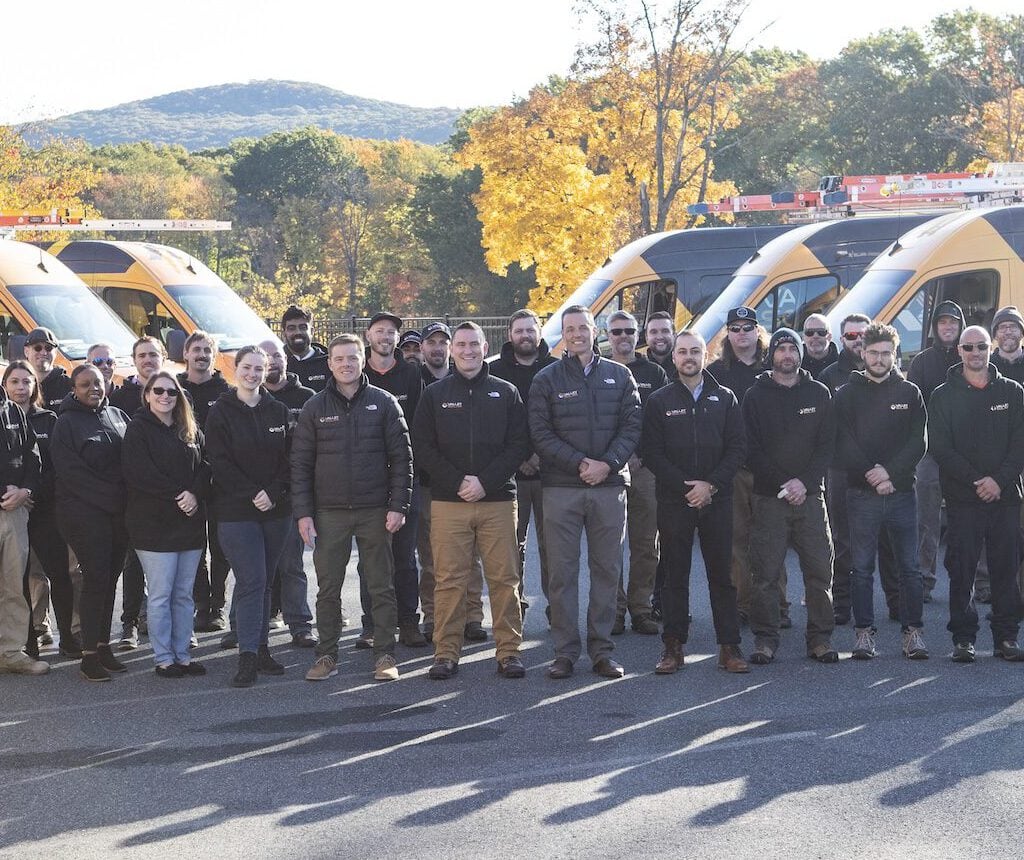 Valley Solar team standing in front of solar-powered service vehicles outdoors.