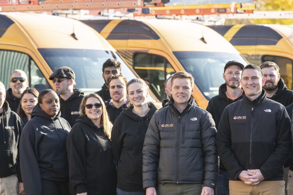 Valley Solar team standing outdoors with solar-powered vehicles, showcasing renewable energy solutions.