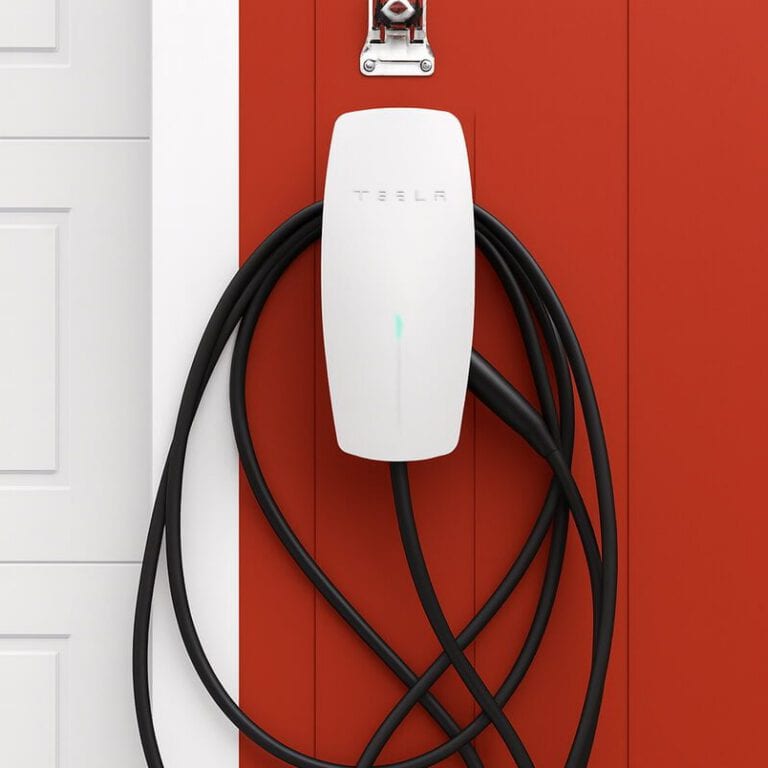 Tesla Powerwall home battery stored on a red wall for solar energy storage.