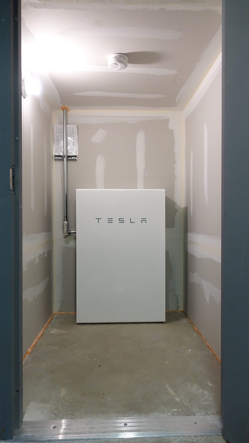 Elevated view of a Tesla Powerwall energy storage system installed inside a utility room.