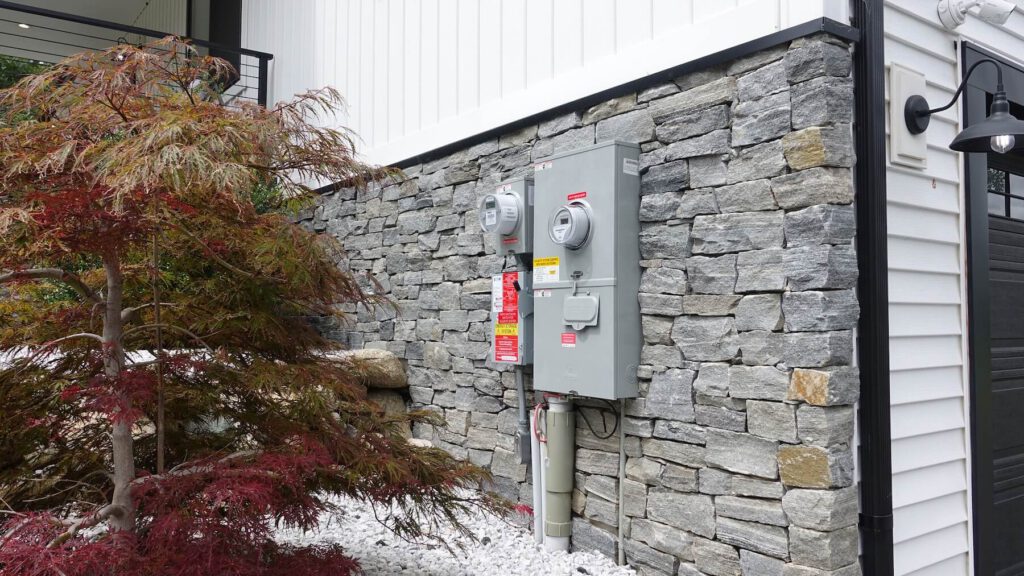 Electric meter and electrical panel installed on a stone wall for solar energy system.