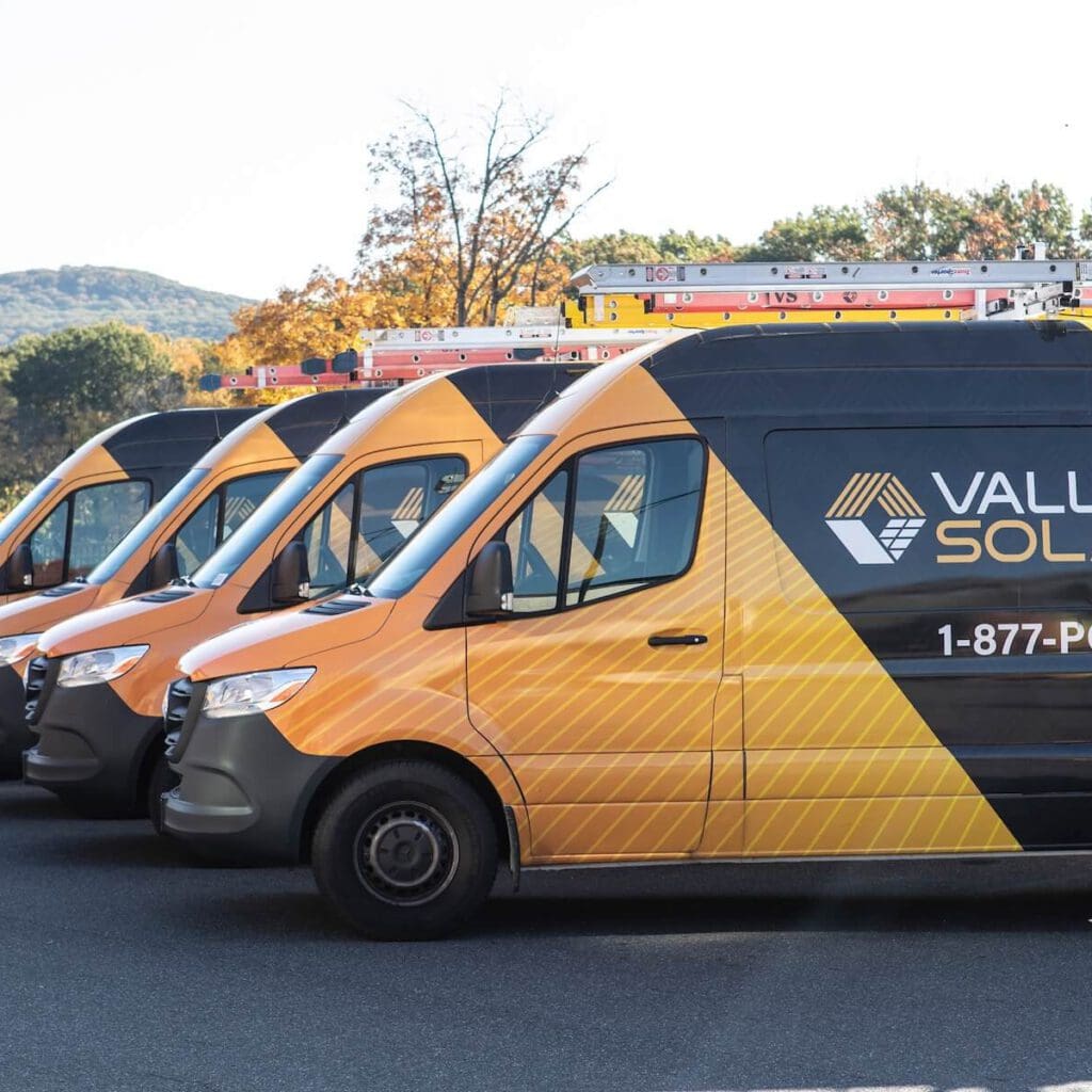 Company branded solar service vans parked outdoors with scenic mountain background.